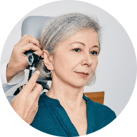 Audiologist looking into woman's ear